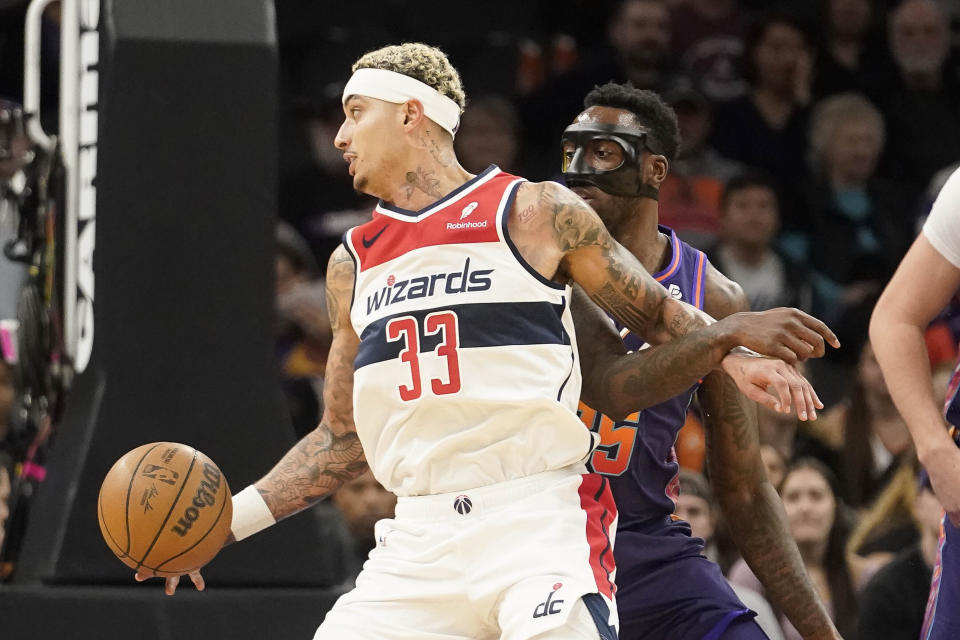 Washington Wizards' Kyle Kuzma (33) gets tied up with Phoenix Suns' Nassir Little (25) during the first half of an NBA basketball game in Phoenix, Sunday, Dec. 17, 2023. (AP Photo/Darryl Webb)