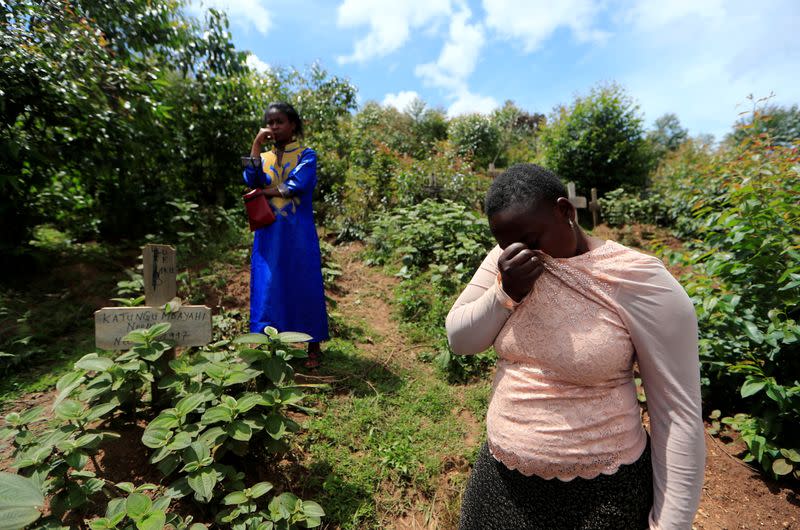 FILE PHOTO: Eugenie Katungu Kavuya and her cousin Noella Masika Vinyinyi react as they stand next to Kavuya's parents' graves, who died of Ebola in Katwa