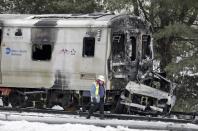 FILE – In this Feb. 4, 2015, file photo, a man wearing a Federal Railroad Administration vest looks over wreckage of a Metro-North Railroad train and an SUV, following a collision that killed five train passengers and the SUV's driver about 20 miles north of New York City in Valhalla, N.Y. Federal Railroad Administrator Sarah Feinberg leaves office Friday, Jan. 20, 2017, after a two-year tenure as the nation's chief railroad regulator, championing safety and technology initiatives that remain a work in progress. (AP Photo/Seth Wenig, File)