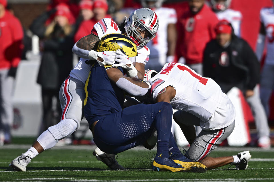 Ohio State linebacker Steele Chambers and cornerback Davison Igbinosun, right, tackle Michigan running back Donovan Edwards during the first half of an NCAA college football game, Saturday, Nov. 25, 2023, in Ann Arbor, Michigan. (AP Photo/David Dermer)