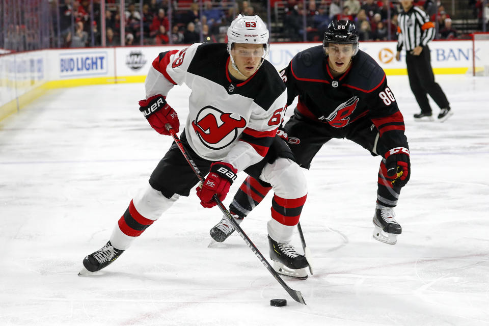 New Jersey Devils' Jesper Bratt (63), of Sweden, protects the puck from Carolina Hurricanes' Teuvo Teravainen (86), of Finland, during the first period of an NHL hockey game in Raleigh, N.C., Friday, Feb. 14, 2020. (AP Photo/Karl B DeBlaker)