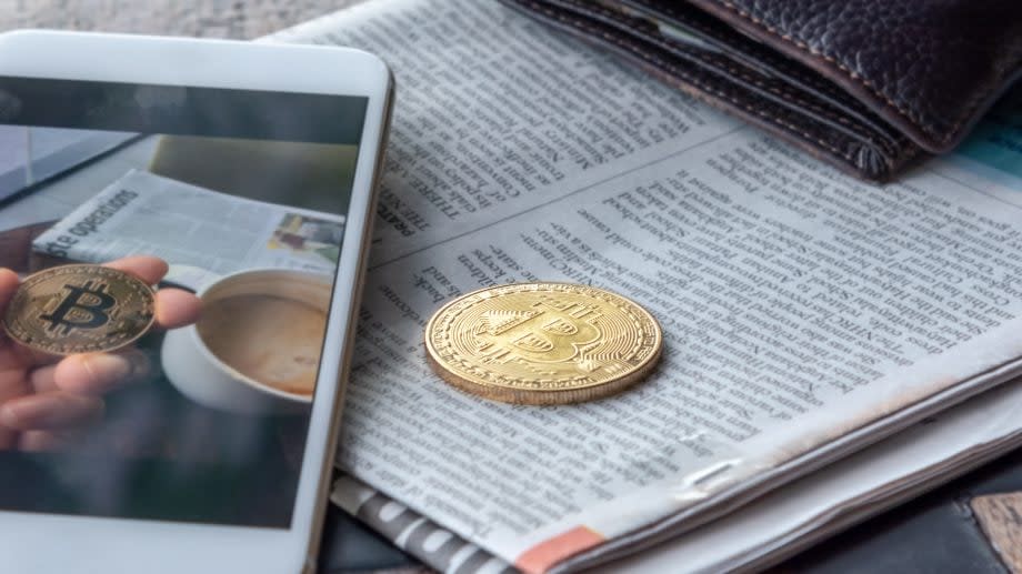 Morning news cryptocurrency with newspaper and bitcoin on mobile screen.