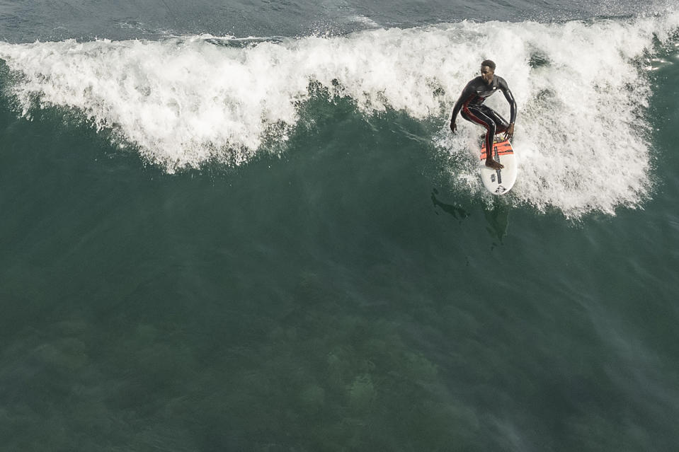 Cherif Fall, Senegal's number one surfer paddles to the wave in the Atlantic Ocean in Dakar, Senegal, Wednesday, Feb. 28, 2024. Instead of training in the waves off his Senegal homeland, Fall was wistfully preferring to be in Puerto Rico, where the last surfing qualifying competition for the Paris Olympics ends on Saturday. Senegal had nobody there to try and claim the last 14 spots for men and women because there was no money to send them, Fall says. (AP Photo/Sylvain Cherkaoui)