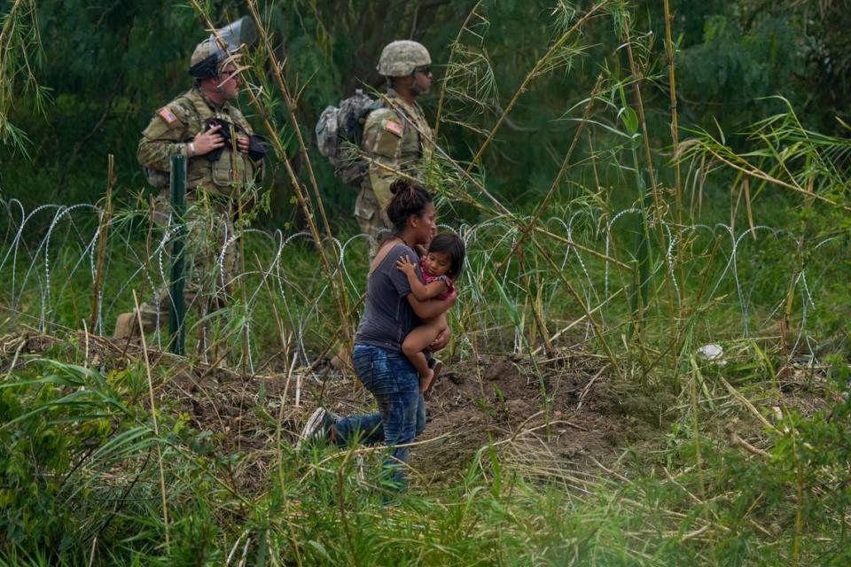 Guardias Nacionales de Texas a lo largo de un tramo de alambre de púas mientras una mujer migrante con un niño intenta cruzar hacia Estados Unidos, en las orillas del Río Grande, como se ve desde Matamoros, México, el jueves 11 de mayo de 2023. Los migrantes se apresuraron a cruzar la frontera con México el jueves con la esperanza de entrar en EEUU en las últimas horas antes de que se levantaran las restricciones de asilo relacionadas con la pandemia. (AP Photo/Fernando Llano)