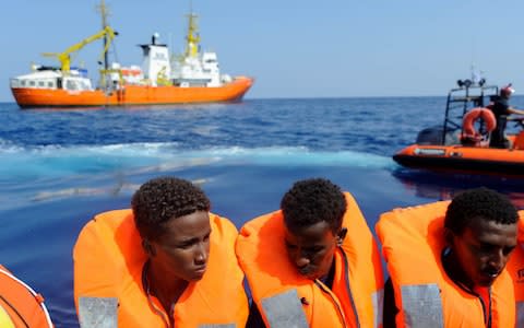 Migrants on a wooden boat are seen after receiving life jackets from crew members of the rescue boat Aquarius - Credit:  GUGLIELMO MANGIAPANE/ AFP