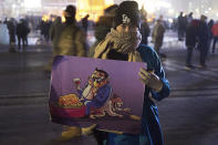 A protester holds up a cartoon depicting inequality during a protest on Sukhbaatar Square in Ulaanbaatar in Mongolia on Monday, Dec. 5, 2022. Protesters angered by allegations of corruption linked to Mongolia's coal trade with China have stormed the State Palace in the capital, demanding dismissals of officials involved in the scandal. (AP Photo/Alexander Nikolskiy)