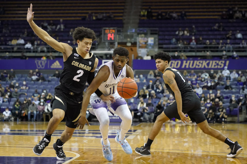 Washington guard Daejon Davis (11) drives around guard KJ Simpson (2) as Colorado guard Julian Hammond III, right, looks on during the first half of an NCAA college basketball game, Thursday, Jan. 27, 2022, in Seattle. (AP Photo/Ted S. Warren)