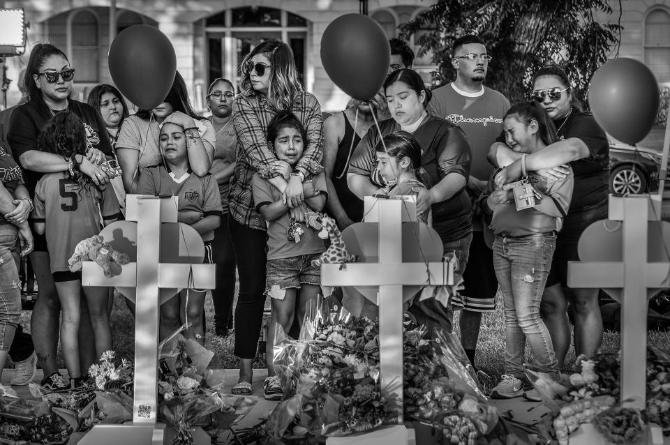 Local children and their parents react to a makeshift memorial in downtown Uvalde, nearby Robb Elementary School, on May 26.<span class="copyright">David Butow—Redux</span>