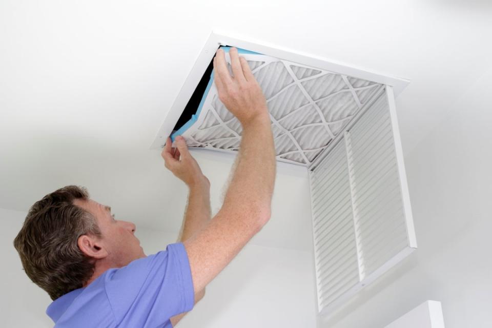 Man replacing air filter on ceiling