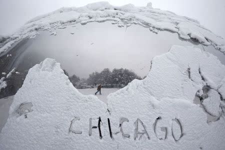 A man is reflected in the sculpture "Cloud Gate" as he walks through Millennium Park during blizzard conditions in Chicago, Illinois February 1, 2015. REUTERS/Jim Young