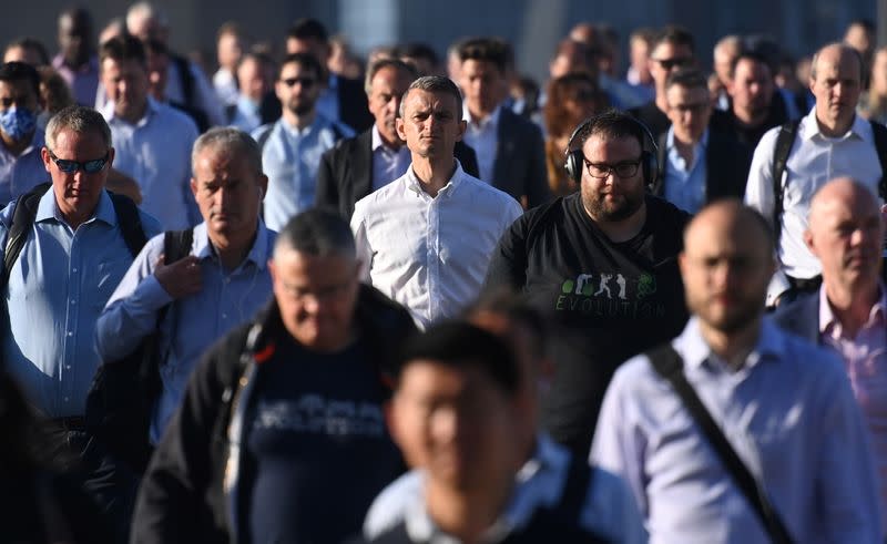 Workers walk towards the City of London financial district as they cross London Bridge during the morning rush hour in London