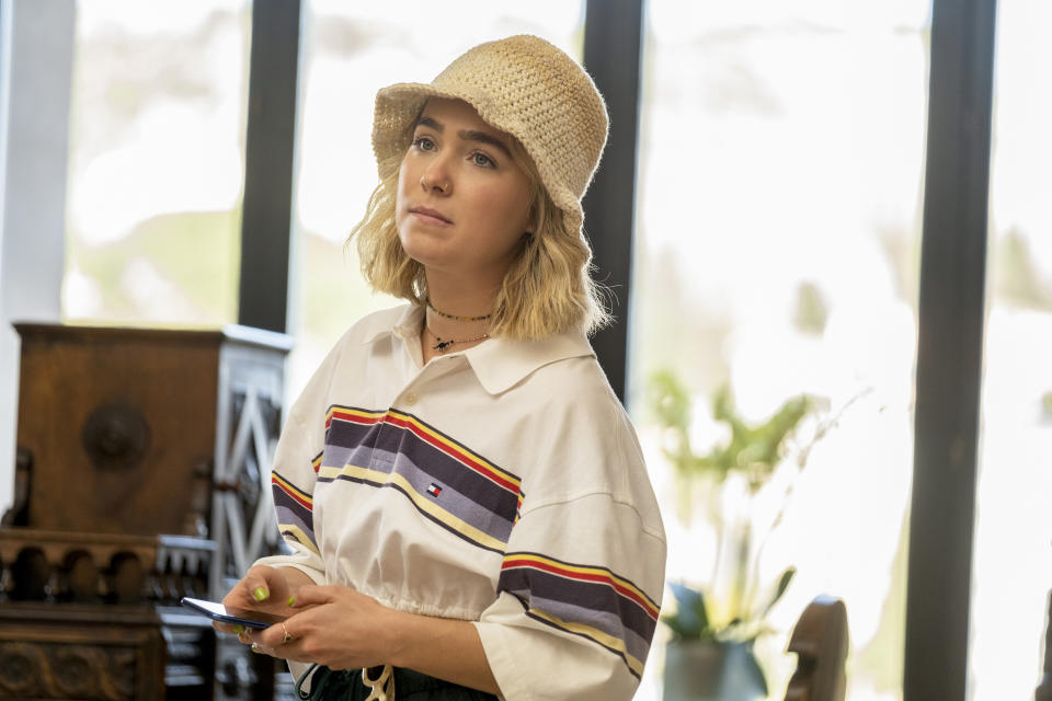 Woman in a striped shirt and hat holding a phone, indoors