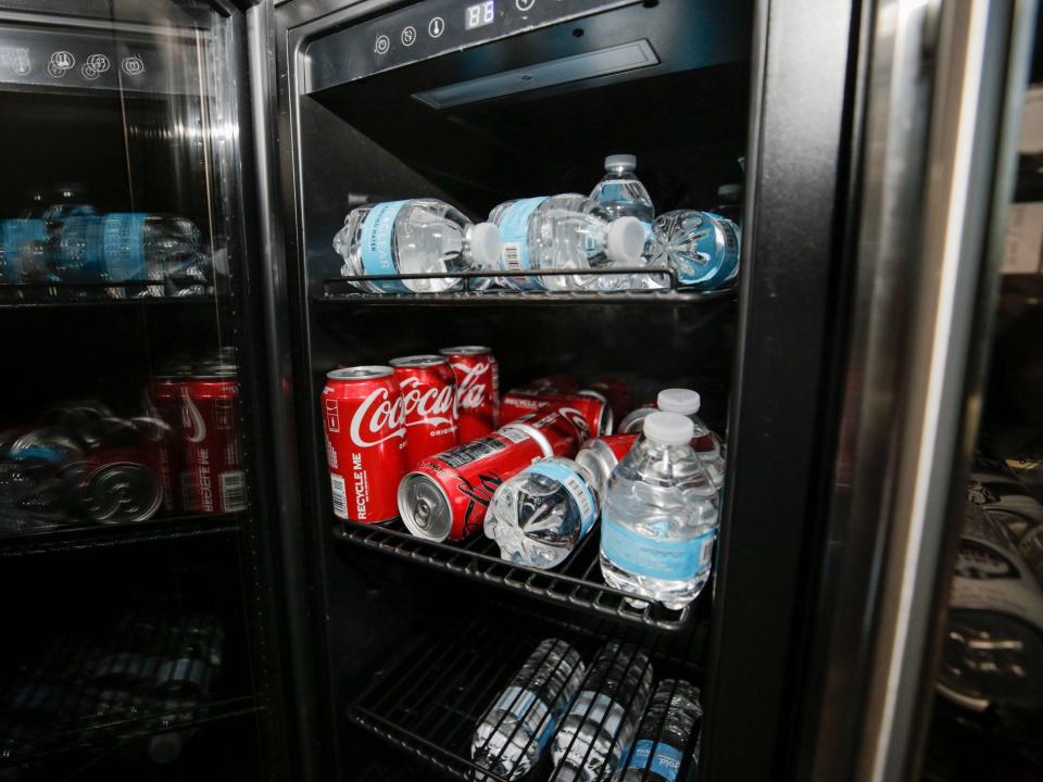 The refrigerator with small water bottles and Coca Cola.