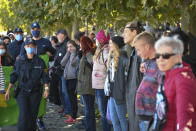 People form a so-called peace human chain, which is supposed to lead through Germany, Austria, Liechtenstein and Switzerland around Lake Constance, while on the left, supporters of the Corona measures are walking past it. (Felix Kaestle/dpa via AP)