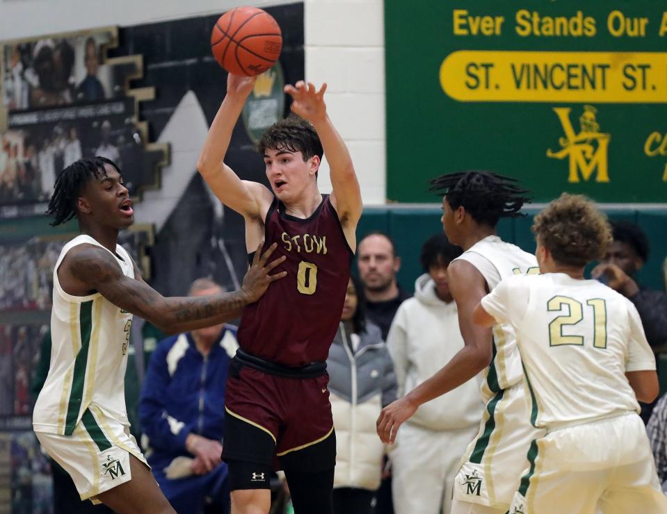 Stow's Reece Raymond-Smith, center, passes against STVM's Daniel Ajose, left, during the second half of a high school basketball game, Tuesday, Jan. 30, 2024, in Akron, Ohio.