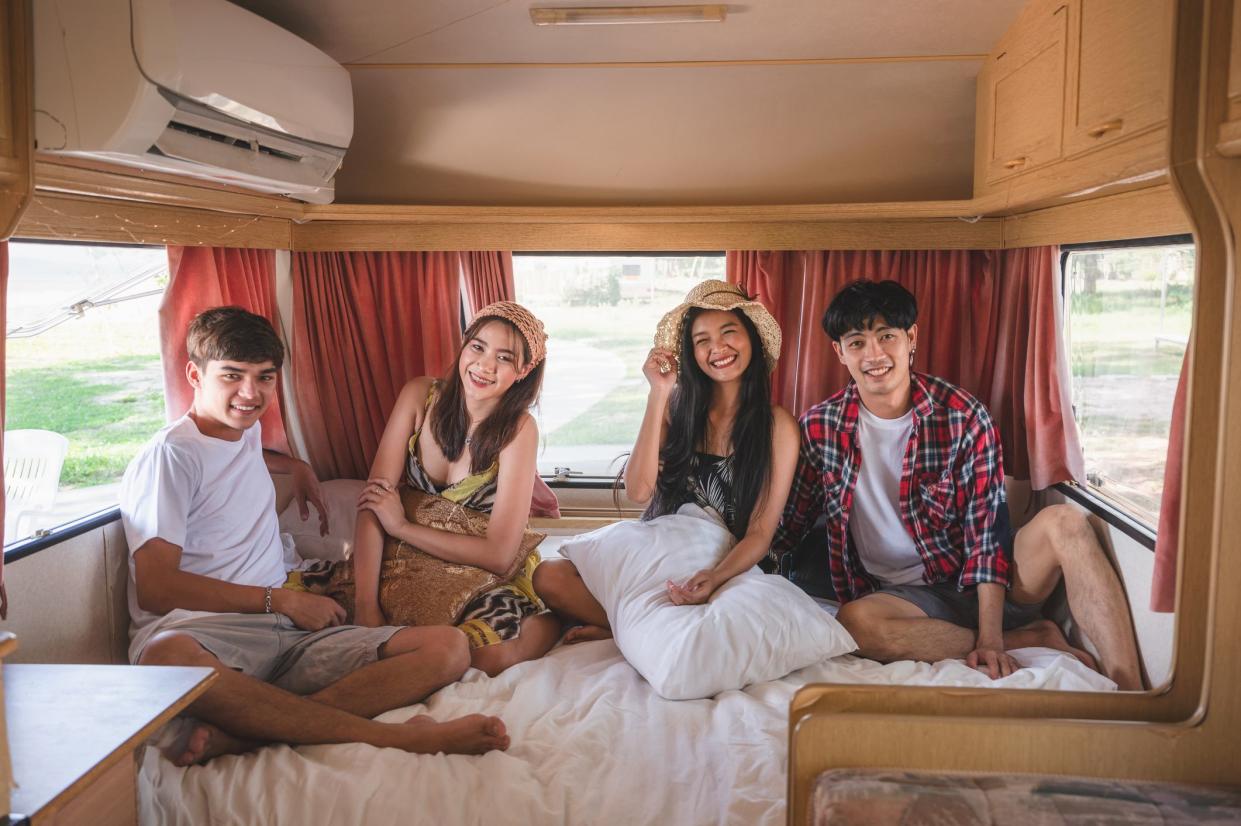 Group of young asian friends having fun inside camper van on weekend