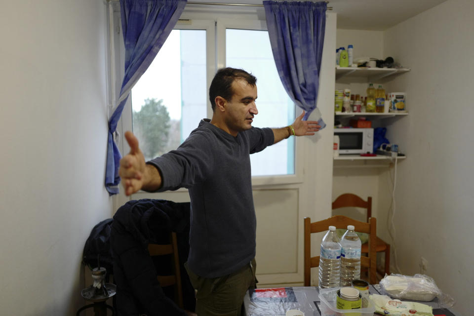 In this photo taken Tuesday, Jan.15, 2019, Ahmed, from Ahwaz in southwest Iran, gestures in a temporary apartment as he visits his wife and children in Calais, northern France, Land, sea and air patrols are combing the beaches, dunes and frigid, murky coastal waters of northern France in a bid to end an unusual high-risk tactic by migrants, mostly Iranians: trying to sneak across the English Channel in rubber rafts. (AP Photo/Michel Spingler)