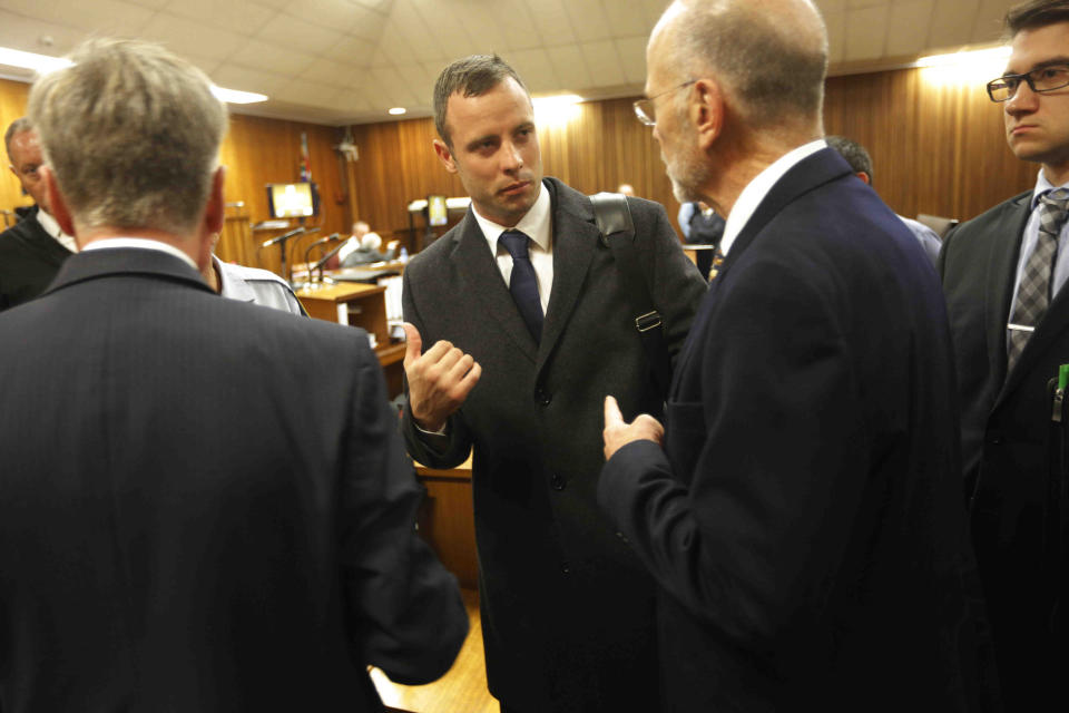 Oscar Pistorius, centre, talks with his uncle Arnold Pistorius, 2nd right, inside court on the second day of his trial at the high court in Pretoria, South Africa, Tuesday, March 4, 2014. Pistorius is charged with murder for the shooting death of his girlfriend, Reeva Steenkamp, on Valentines Day in 2013. (AP Photo/Kim Ludbrook,Pool)