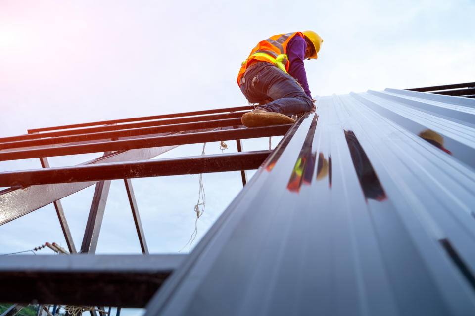 Construction worker in construction site,Roofer worker in special protective workwear and gloves are working on top of the new roof.