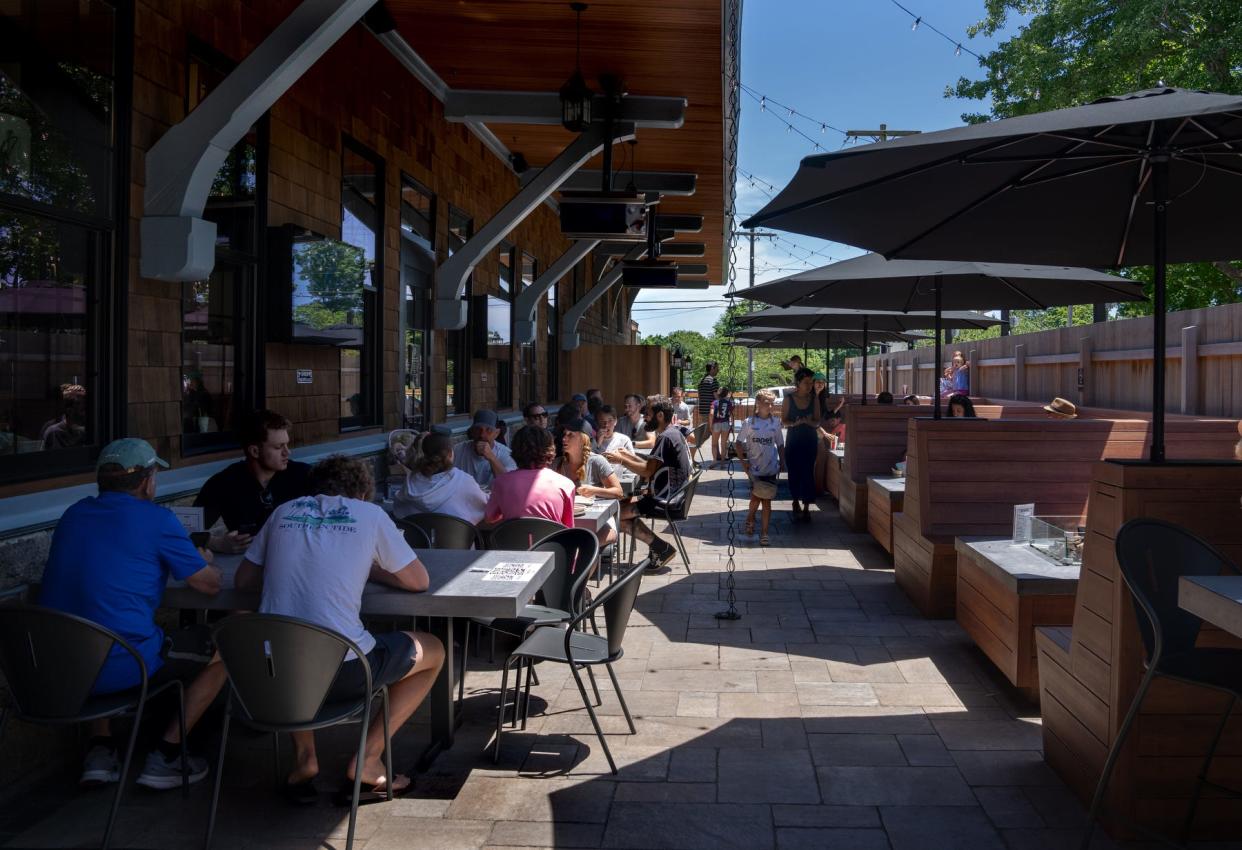 Visitors enjoy the open air and big screen TV at the outdoor dining area at Boon Street Market.