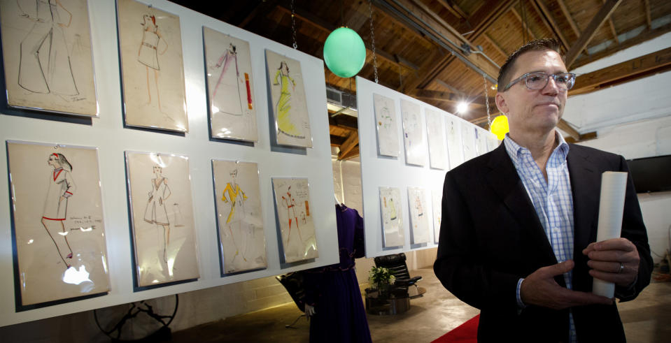 In this Monday, Dec. 30, 2013 photo, auctioneer Rico Baca stands beside some of Karl Lagerfeld's drawings that will be sold in West Palm Beach, Fla. The signature of designer Lagerfeld is adding an extra splash of glamour to a collection of fashion sketches up for auction in Florida. The half-century-old archive from the House of Tiziani in Rome will be sold Jan. 11, 2014, at Palm Beach Modern Auctions. In the 1960s, Tiziani designed movie costumes and clothing for Elizabeth Taylor and other celebrities. (AP Photo/J Pat Carter)