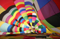 WOOTTON, UNITED KINGDOM - APRIL 07: A hot air balloonist makes preparations for departure from Lydden Hill race circuit near Canterbury to take part in a mass crossing of the Channel on April 7, 2011 in Wootton, England. 51 balloonists of various nationalities from across Europe took off from Kent making for Calais, France at about 7am. It is the first time a Guinness World Record bid has been made for "the largest group of hot air balloons to make the Channel crossing". (Photo by Oli Scarff/Getty Images)