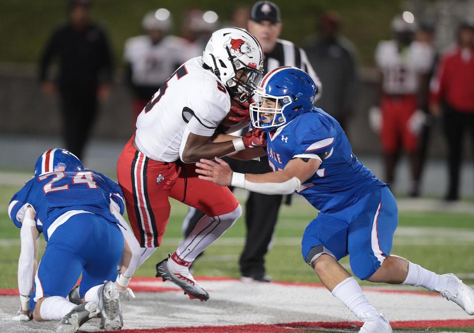 McKinley's Dante McClellan fights for yardage in the second half with defense from Lake's Dylan Snyder, left, and Charlie Christopher at Lake Friday , September 30, 2022.