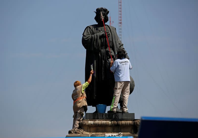 Workers clean the statue of Italian explorer Cristobal Colon, also known as Christopher Columbus, in Mexico City