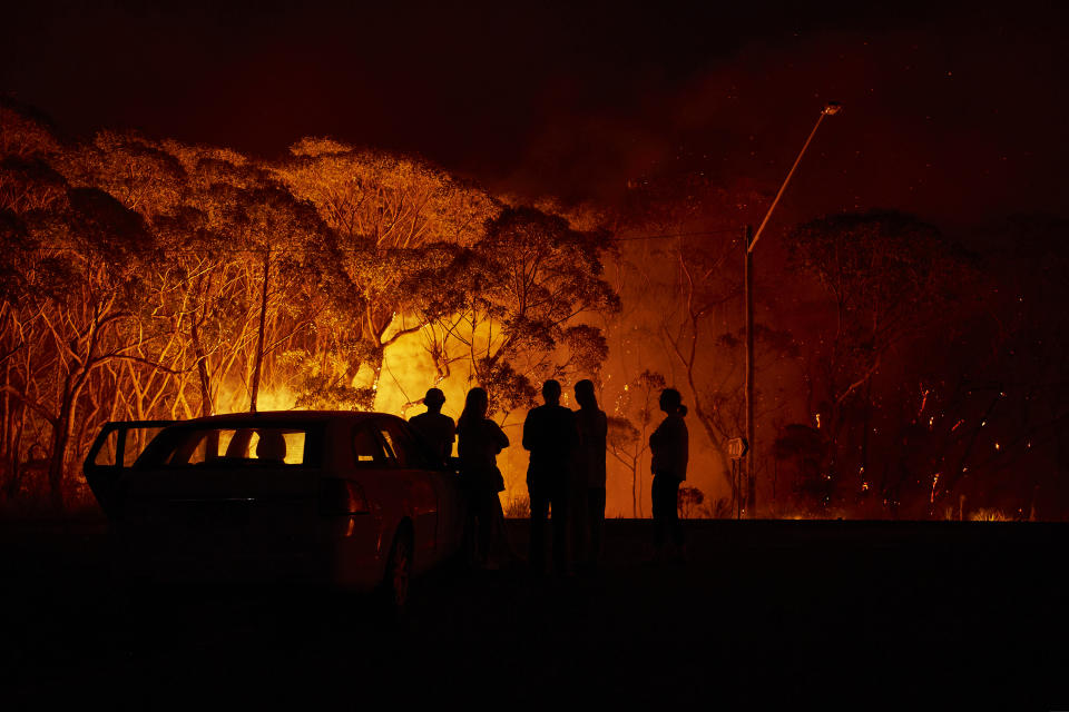 LAKE TABOURIE, AUSTRALIA - JANUARY 04: Residents look on as flames burn through bush on January 04, 2020 in Lake Tabourie, Australia. A state of emergency has been declared across NSW with dangerous fire conditions forecast for Saturday, as more than 140 bushfires continue to burn. There have been eight confirmed deaths in NSW since Monday 30 December. 1365 homes have been lost, while 3.6 million hectares have been burnt this fire season. (Photo by Brett Hemmings/Getty Images)