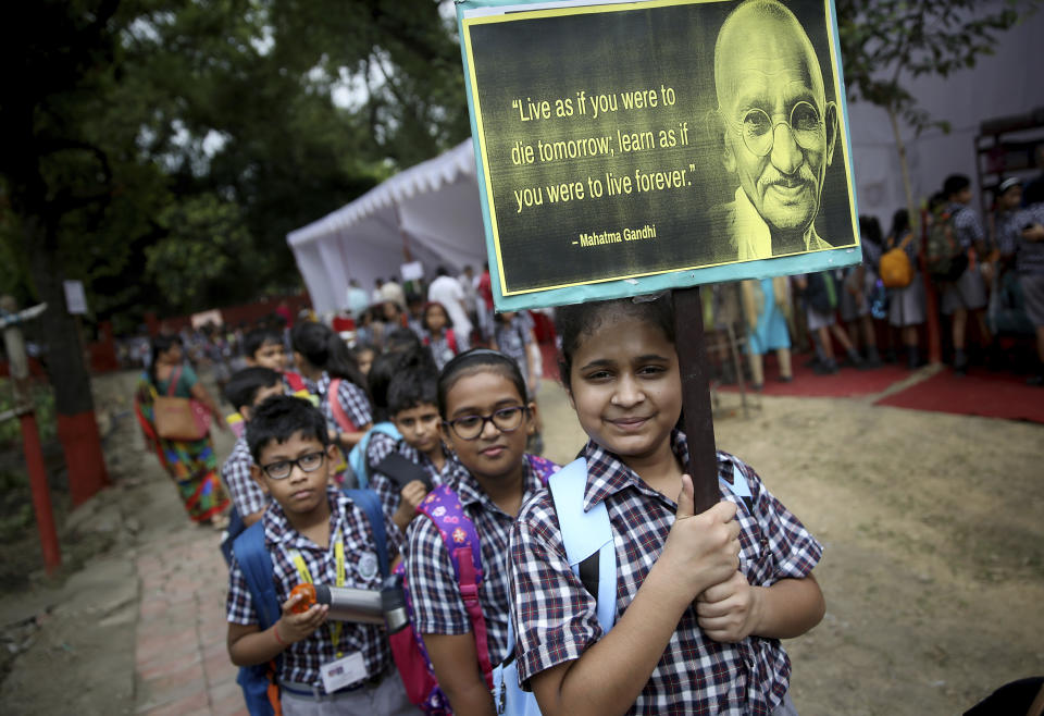 A schoolgirl holds a placard as they participate in an event to celebrate the 150th birth anniversary of India's independence leader Mahatma Gandhi in New Delhi, India, Tuesday, Oct. 1, 2019. India’s biggest political parties are vying for the political legacy of iconic independence leader Mahatma Gandhi on the 150th anniversary of his birth. (AP Photo/Altaf Qadri)