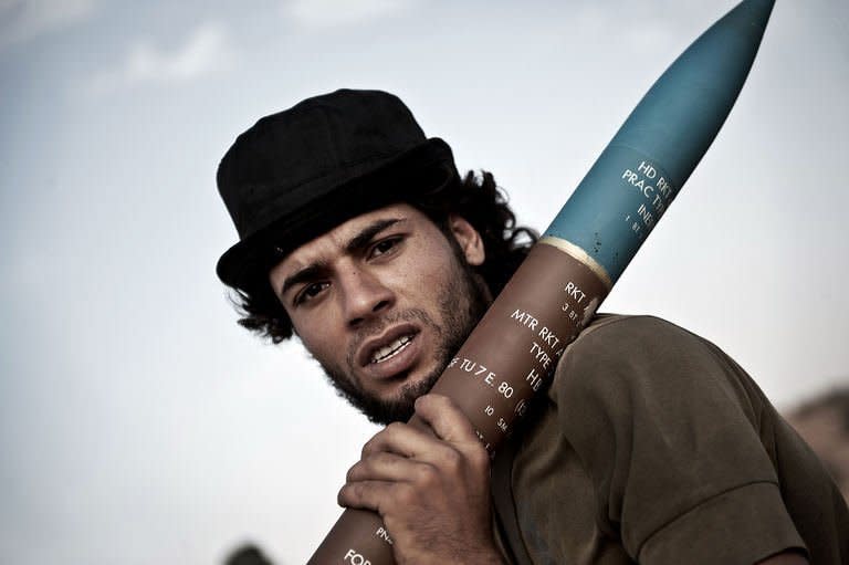 A Libyan rebel fighter carries a rocket at the front line near the southwest desert hamlet of Gualish on July 24. Libya on Monday accused NATO of killing at least seven people in an air raid on a medical clinic in Zliten east of Tripoli, as the top US officer spoke of "stalemate" in NATO's campaign