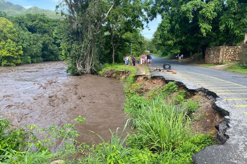 People watch a river swell due to heavy rains following the passage of Hurricane Beryl on the road from Cumana to Cumanacoa, Sucre State, Venezuela, on July 2, 2024.