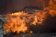 FILE - Buildings burn in Chinatown during two days of riots, sparked by underlying grievances, including concerns of the country's increasing links with China, Honiara, Solomon Islands on Nov. 26, 2021. China’s Foreign Minister Wang Yi is visiting the South Pacific with a 20-person delegation this week in a display of Beijing's growing military and diplomatic presence in the region. (AP Photo/Piringi Charley, File)