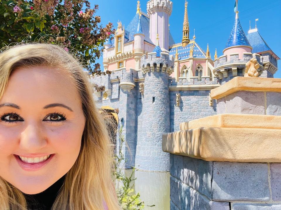 carly posing for a selfie at disneyland in front of the castle