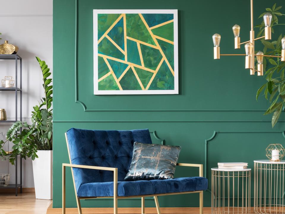 Green wall and a blue chair with a large green abstract print in background