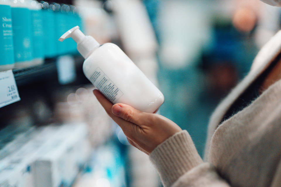 A hand holding a bottle in a store aisle