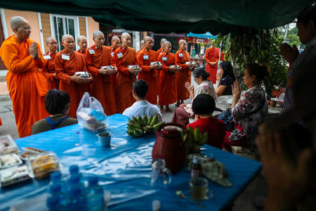 Novice monks pray after receiving food offerings from people in Nakhon Pathom province, Thailand, December 7, 2018. REUTERS/Athit Perawongmetha