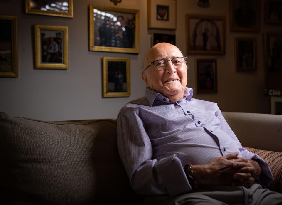 Holocaust survivor David Wolnerman, 95, smiles for a photo at his home in Des Moines. Behind him are decades of family photos.