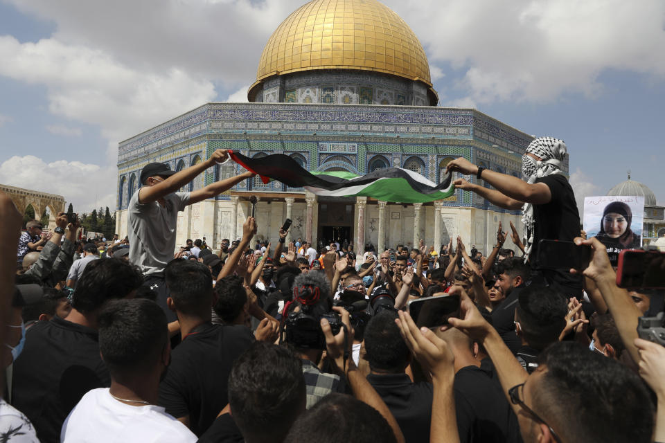 Protesters wave a Palestinian flag and one in the crowd holds a spoon, which has become a symbol celebrating the six Palestinian prisoners who tunneled out of Gilboa Prison, after Friday prayers at the Dome of the Rock Mosque in the Al Aqsa Mosque compound in in the Old City of Jerusalem, Friday, Sept. 10, 2021. (AP Photo/Mahmoud Illean)