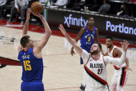 Denver Nuggets center Nikola Jokic, left, hits a shot over Portland Trail Blazers center Jusuf Nurkic (27) during the first half of an NBA basketball game in Portland, Ore., Wednesday, April 21, 2021. (AP Photo/Steve Dykes)