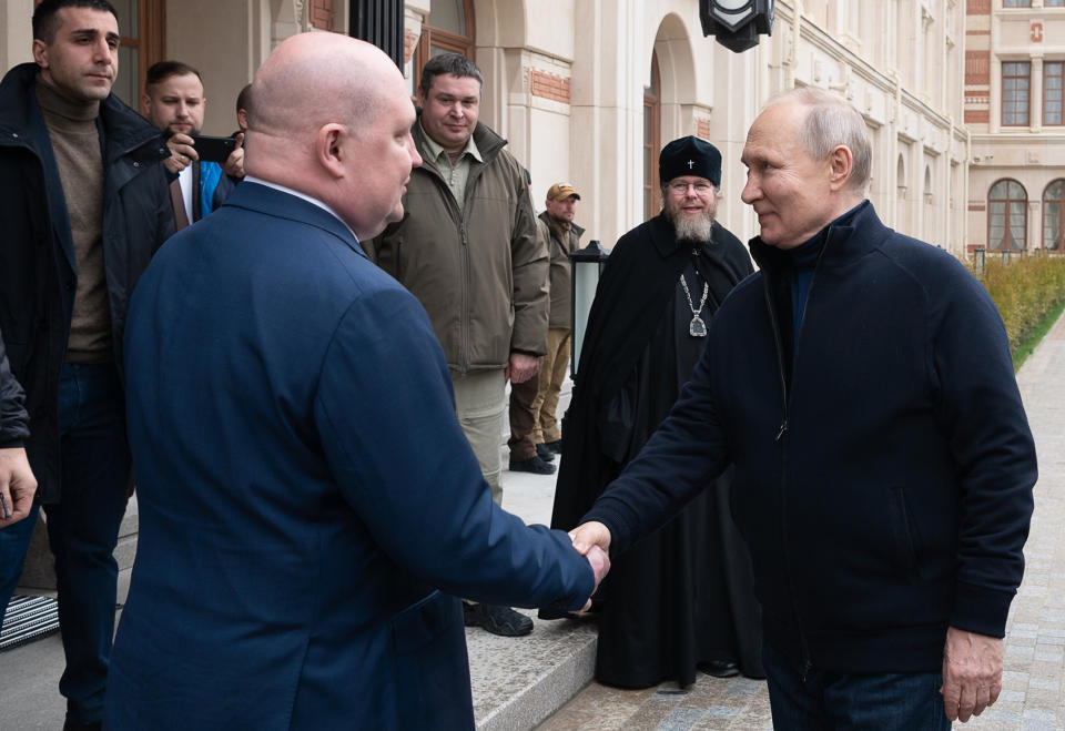 Russian President Vladimir Putin shakes hands with Governor of Sevastopol Mikhail Razvozhayev as he arrives to visit the Children's Art and Aesthetic center in Sevastopol, Crimea, Saturday, March 18, 2023. Putin has traveled to Crimea to mark the ninth anniversary of the Black Sea peninsula's annexation from Ukraine. (Sputnik, Kremlin Press Service Pool Photo via AP)