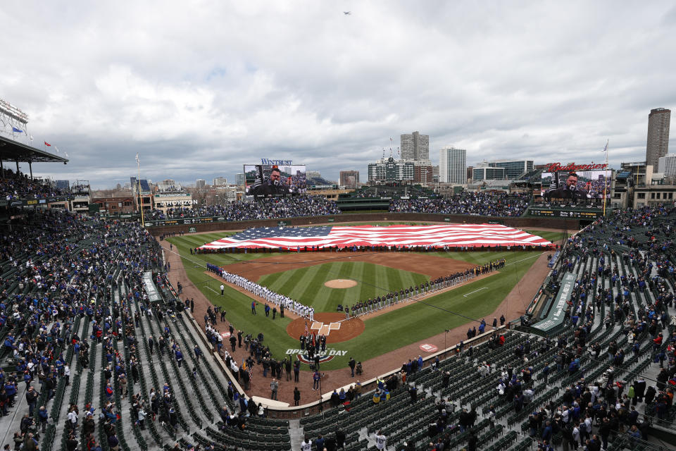 Chicago Cubs and Milwaukee Brewers players stand on the sidelines during the national anthem before the Cubs home-opener baseball game, Thursday, April 7, 2022, in Chicago. (AP Photo/Kamil Krzaczynski)