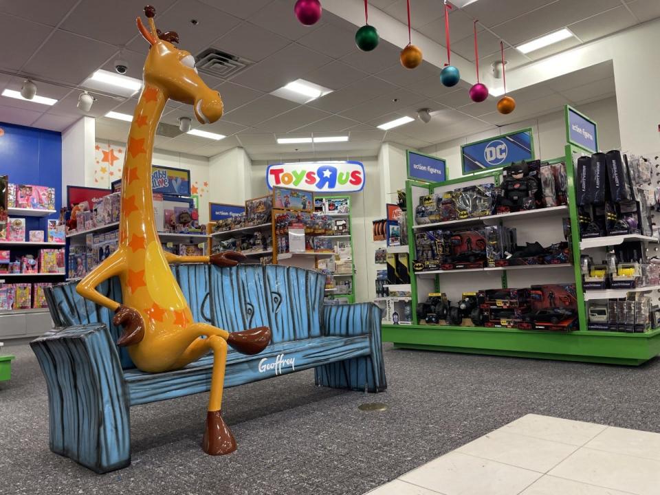 A statue of Toys R Us mascot Geoffrey the giraffe waits for customers' photographs beside shelves of toys inside the Macy's in Augusta Mall, Oct. 19, 2022. The retailer that filed for bankruptcy in 2017 has reopened inside Macy's nationwide.