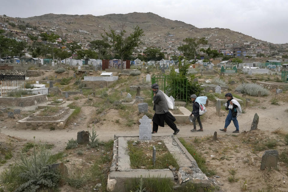 An Afghan man goes home with his sons through the cemetery in Kabul, Afghanistan, Sunday, May 15, 2022. There are cemeteries all over Afghanistan's capital, Kabul, many of them filled with the dead from the country's decades of war. They are incorporated casually into Afghans' lives. They provide open spaces where children play football or cricket or fly kites, where adults hang out, smoking, talking and joking, since there are few public parks. (AP Photo/Ebrahim Noroozi)