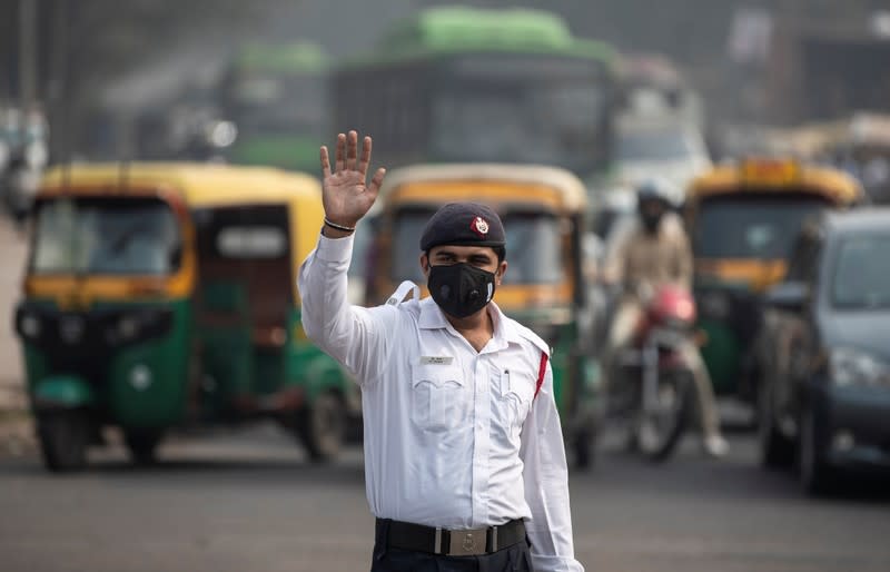 A traffic policeman wears a mask to protect himself from air pollution at a junction during restrictions on private vehicles based on registration plates on a smoggy morning in New Delhi