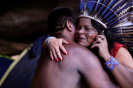 Indian Leader Sonia Guajajara embraces a member of her tribe as she talks on her mobile phone at the Terra Livre camp, or Free Land camp, in Brasilia, Brazil April 24, 2019. REUTERS/Nacho Doce
