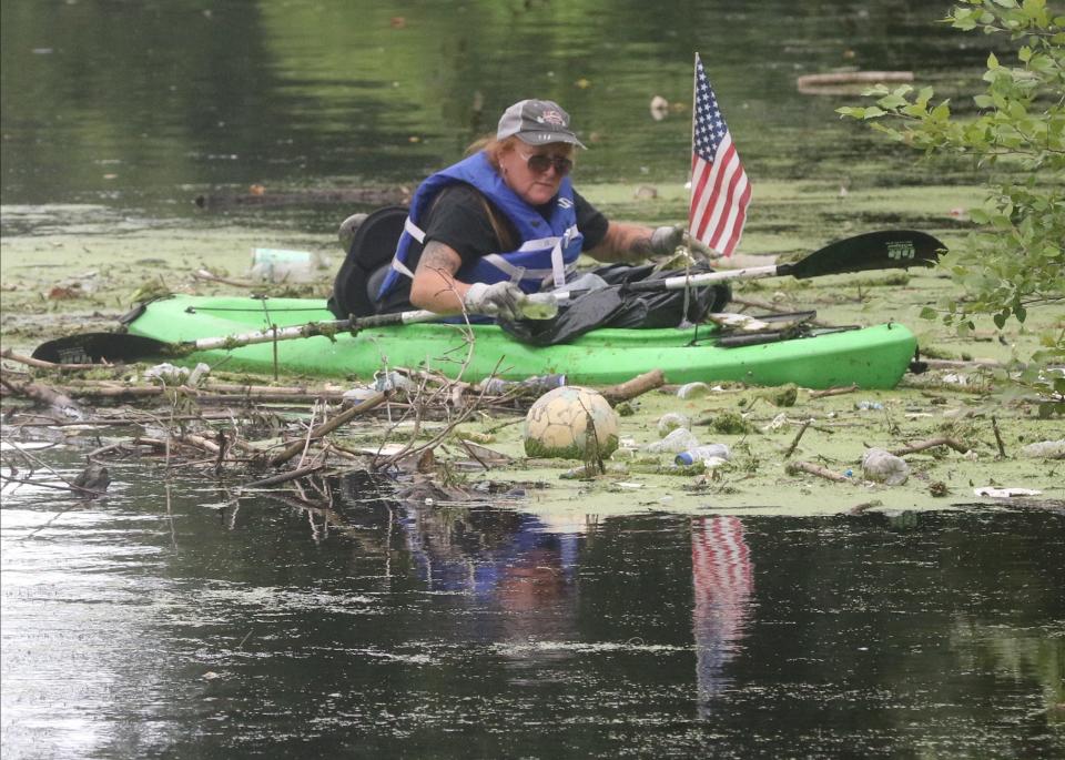 Barbara Holstein of Montague in a kayak pulls garbage out of the Passaic River. Volunteers took part in City of Water Day by participating in a river cleanup of the Passaic River at Westside Park.