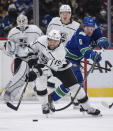 Los Angeles Kings' Alex Iafallo (19) reaches for the puck in front of Vancouver Canucks' Brock Boeser (6) during first-period NHL hockey game action in Vancouver, British Columbia, Monday, Dec. 6, 2021. Darryl Dyck/The Canadian Press via AP)