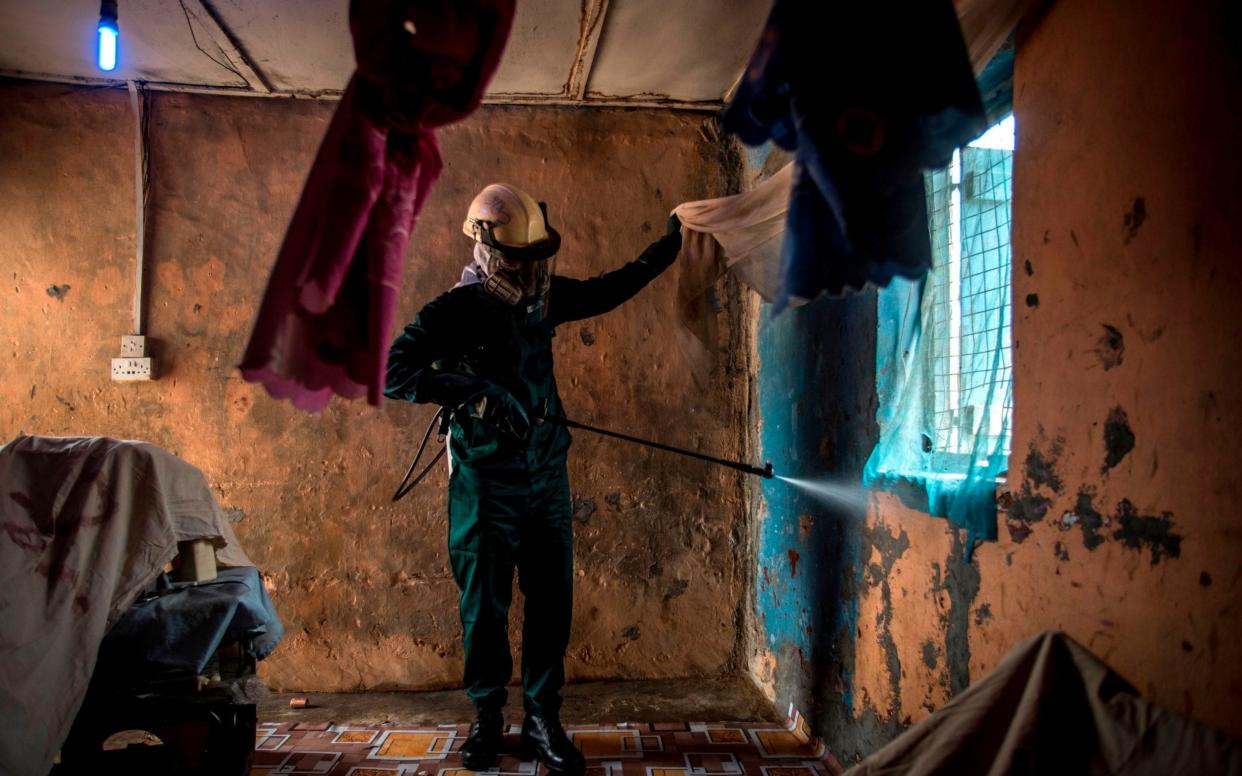 A worker sprays insecticide inside a house in the Ashanti region of Ghana - AFP