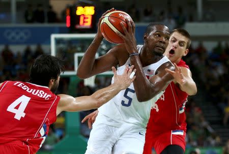 Kevin Durant drives through Milos Teodosic and Nikola Jokic of Serbia. REUTERS/Marko Djurica